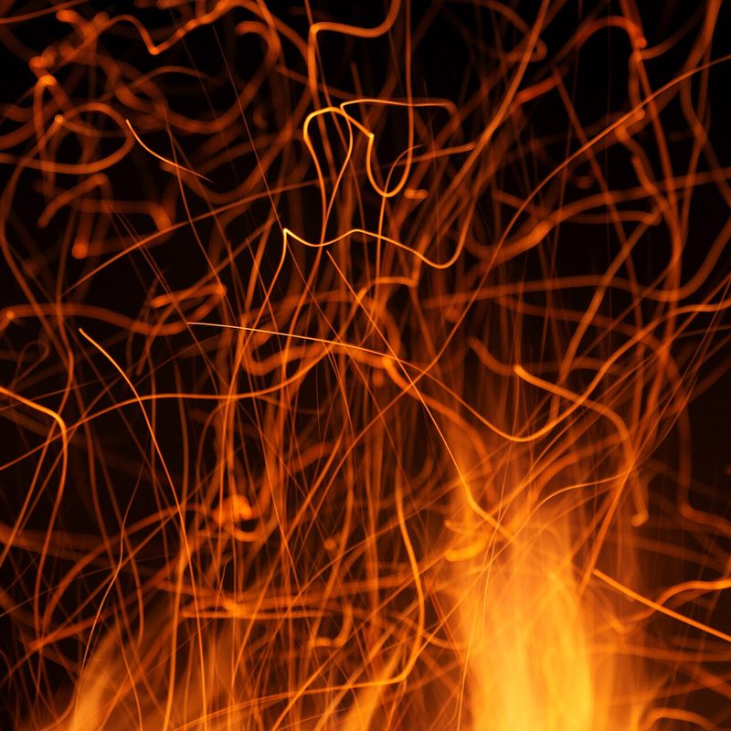 Sparks streaming upward from a campfire against the dark