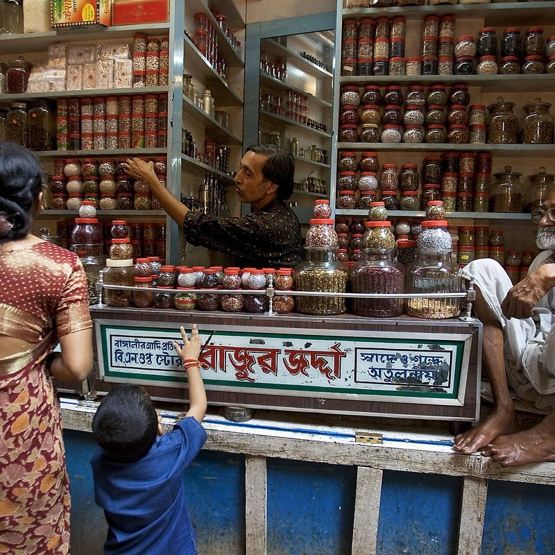 Shoppers at a spice shop counter lined with jars in Varanasi