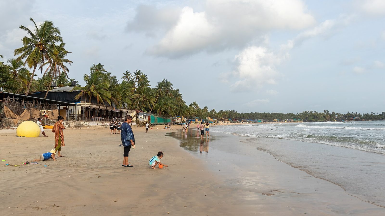 Palm trees and beach shacks along the sand at Palolem beach in South Goa