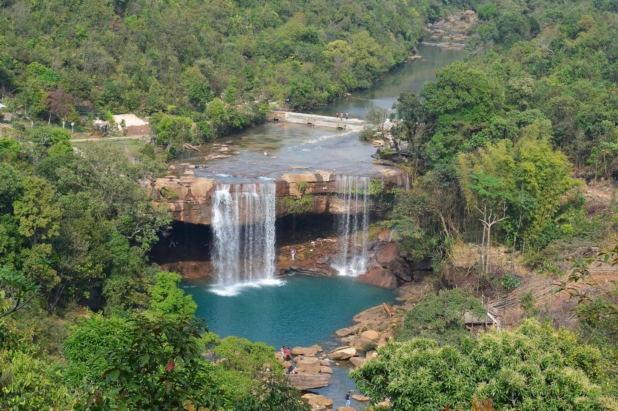 The Khrangsuri waterfall in Meghalaya dropping into a turquoise pool ringed by jungle