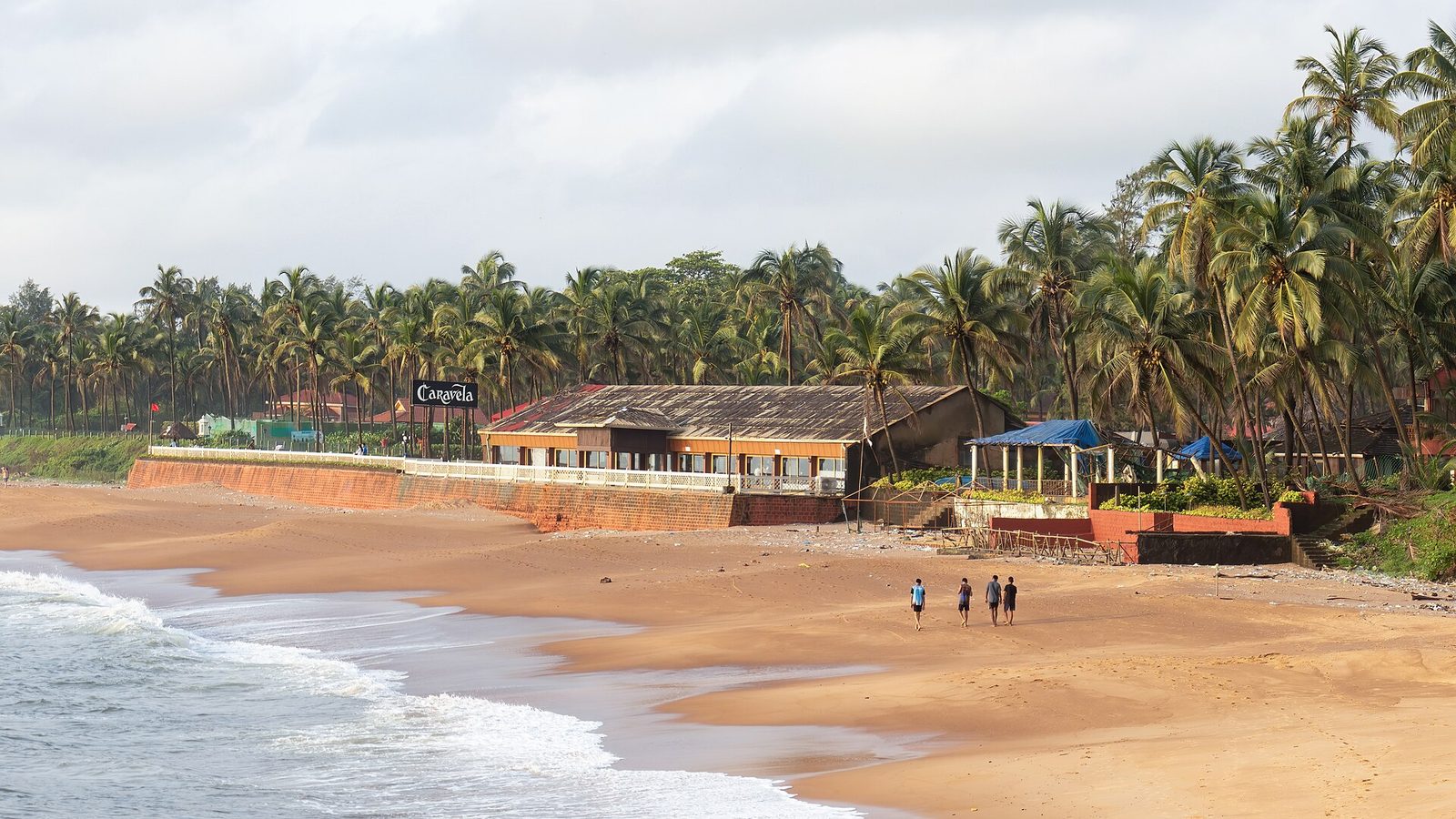 Palm-backed beach shacks above the surf at Sinquerim beach in Goa, late in the day